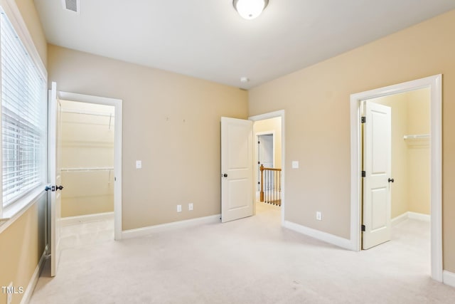 unfurnished bedroom featuring carpet floors, a walk in closet, and a closet