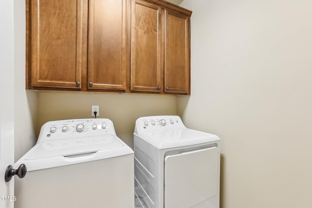 clothes washing area featuring cabinet space and separate washer and dryer