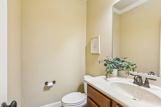 half bath featuring crown molding, vanity, and toilet