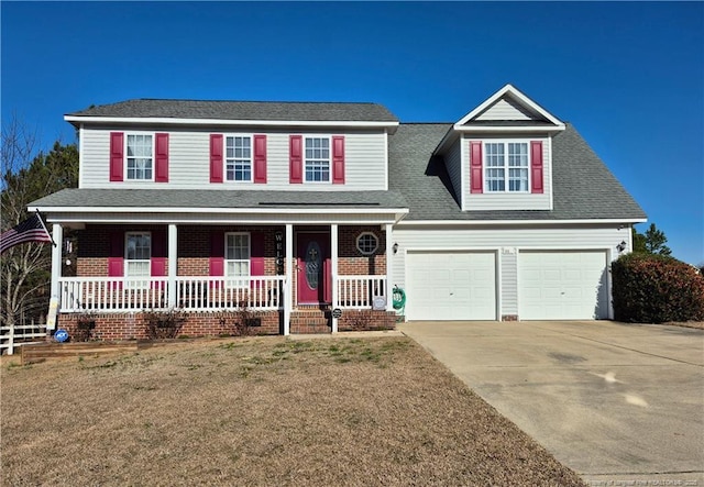 traditional-style home with driveway, covered porch, roof with shingles, and a front yard