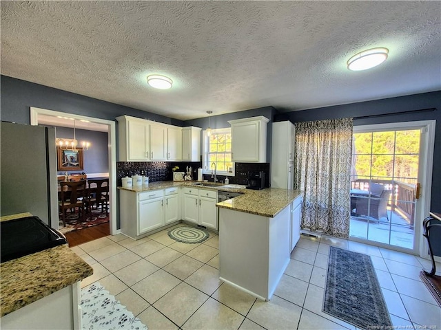 11 Scotland Dr, Spring Lake, NC 28390 - kitchen featuring freestanding refrigerator, light tile patterned floors, a peninsula, white cabinetry, and a chandelier