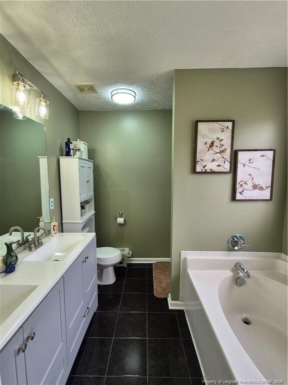 11 Scotland Dr, Spring Lake, NC 28390 - bathroom with tile patterned floors, toilet, a bath, visible vents, and a sink