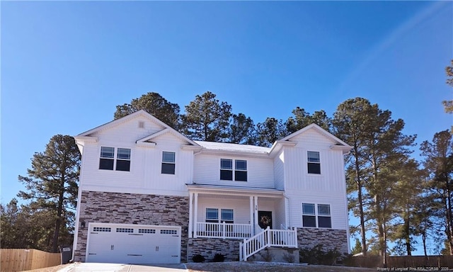 view of front of house featuring an attached garage, covered porch, fence, stone siding, and driveway