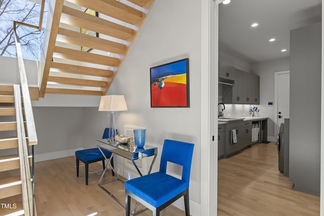 interior space with light wood finished floors, baseboards, stairway, recessed lighting, and a sink