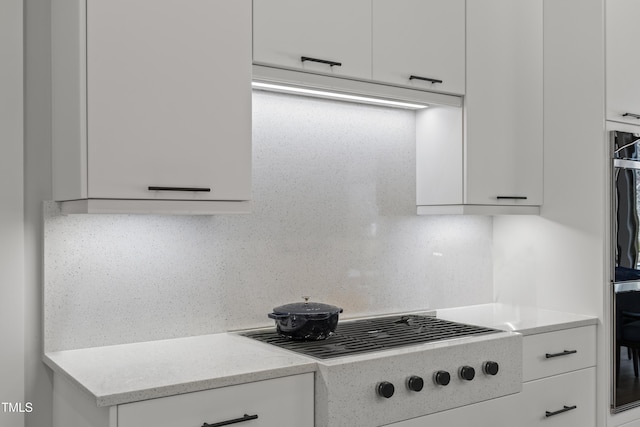 kitchen featuring cooktop, white cabinetry, and light stone countertops