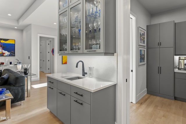 kitchen featuring a sink, light wood finished floors, and gray cabinetry