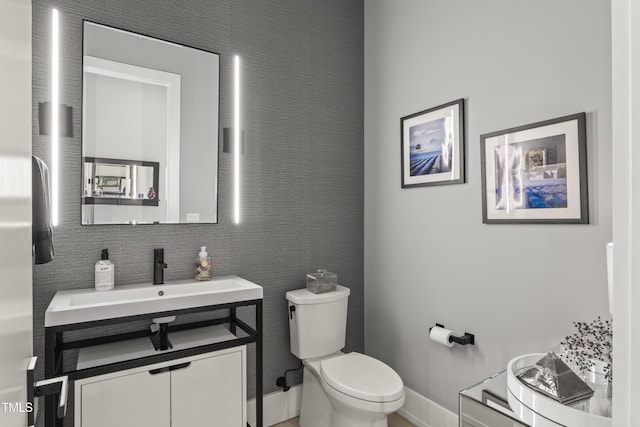 bathroom featuring baseboards, toilet, and vanity