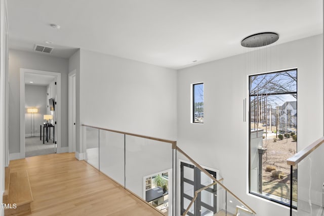 corridor with wood finished floors, visible vents, and baseboards