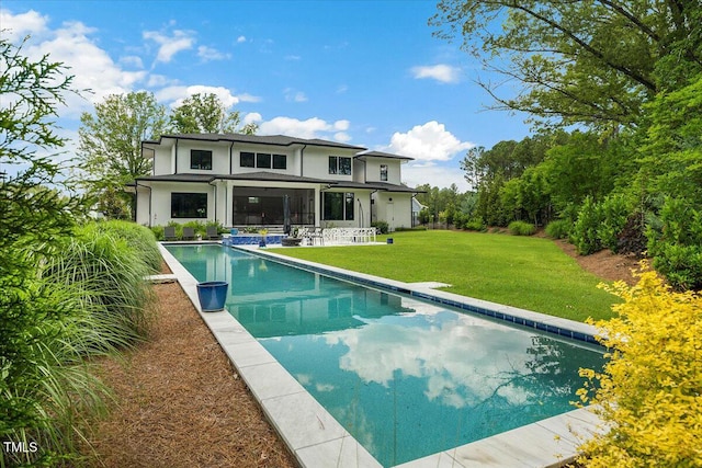 rear view of house featuring an outdoor pool, stucco siding, and a lawn