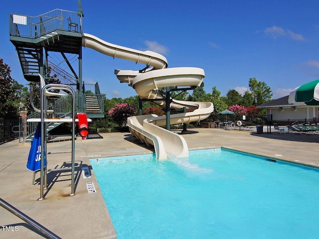 pool with a water slide, a patio area, and stairway