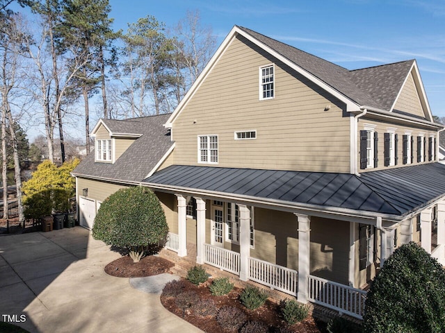 view of front of home with a garage, a shingled roof, metal roof, covered porch, and a standing seam roof