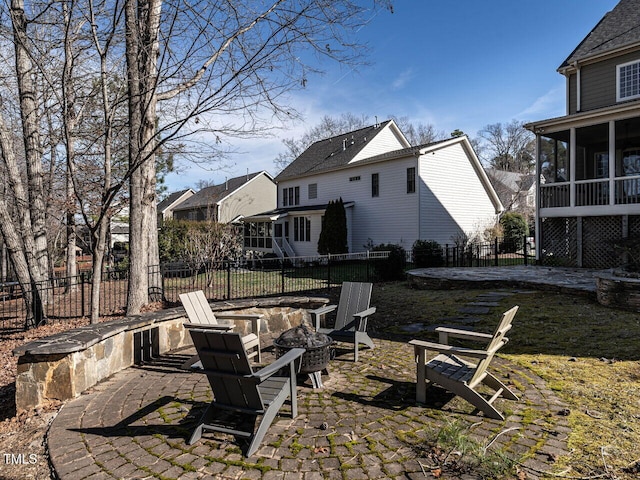 rear view of house featuring a fire pit, a patio area, fence, and a sunroom