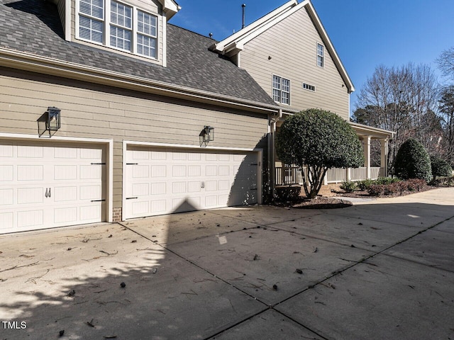 view of property exterior featuring a garage, concrete driveway, and roof with shingles