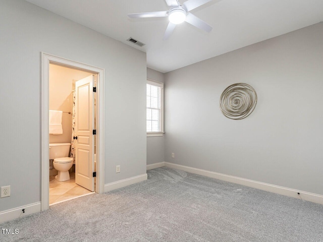 unfurnished bedroom featuring light carpet, ensuite bath, visible vents, and baseboards