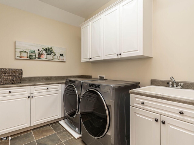 washroom with dark tile patterned flooring, separate washer and dryer, a sink, and cabinet space