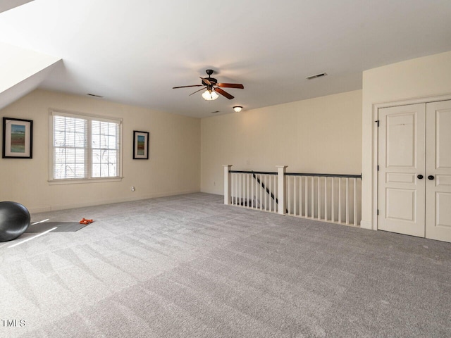 spare room with lofted ceiling, visible vents, ceiling fan, and carpet flooring