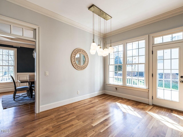 unfurnished dining area with a notable chandelier, baseboards, ornamental molding, and wood finished floors