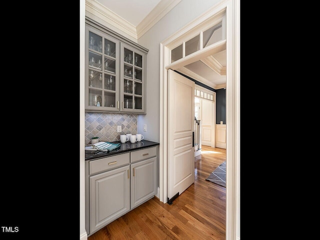 bar with dark wood-style floors, ornamental molding, and decorative backsplash