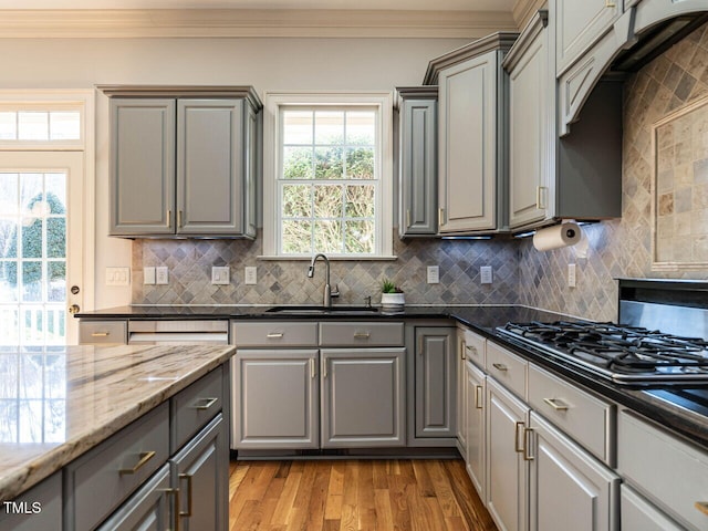 kitchen with crown molding, gray cabinets, a sink, and dark stone countertops