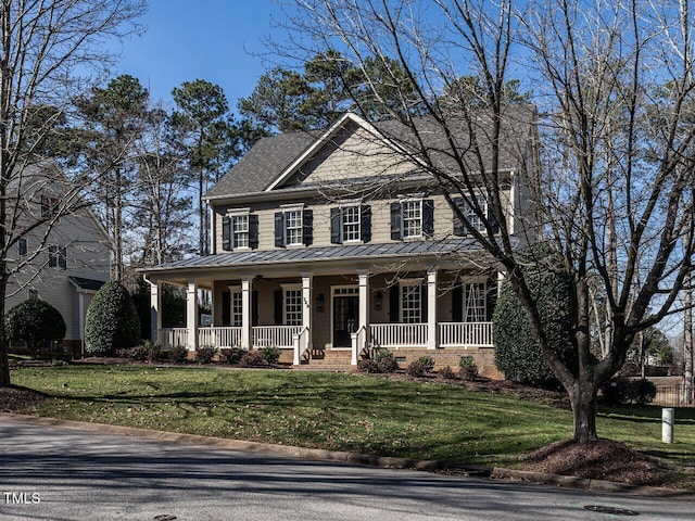 view of front of property featuring a front yard, covered porch, metal roof, and a standing seam roof