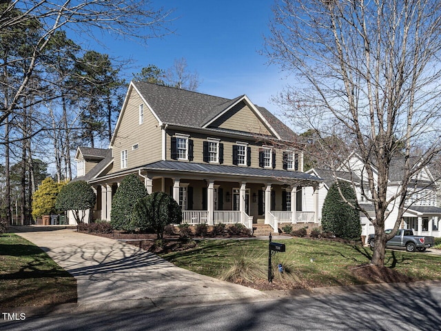 view of front facade featuring a porch, concrete driveway, a standing seam roof, metal roof, and a front lawn