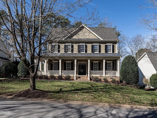 colonial inspired home with a standing seam roof, metal roof, a porch, and a front lawn