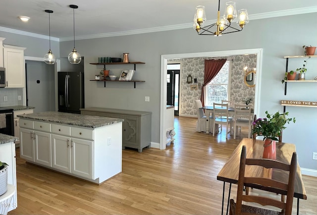 kitchen with dark stone counters, pendant lighting, white cabinetry, and black fridge