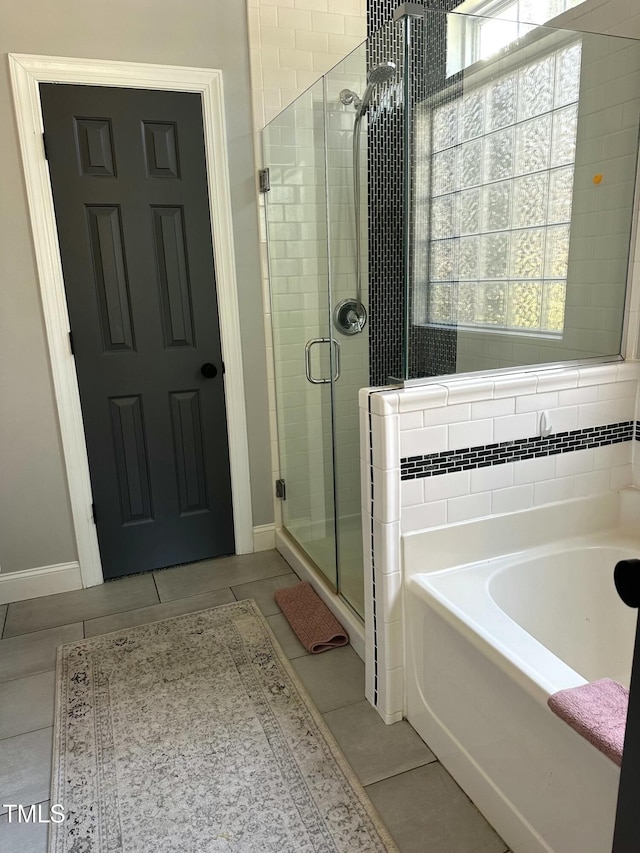 bathroom with a shower stall, a bath, and tile patterned floors