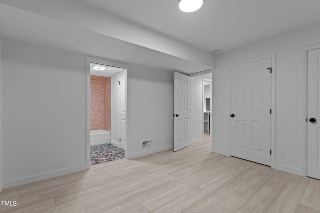 unfurnished bedroom with baseboards, visible vents, ensuite bath, and light wood finished floors