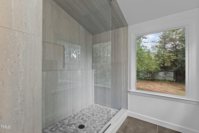 bathroom with tile patterned flooring, baseboards, vaulted ceiling, and tiled shower