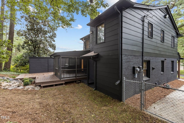 view of side of home with brick siding, fence, and a deck