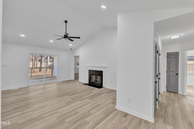 unfurnished living room with recessed lighting, a fireplace with flush hearth, light wood-style floors, vaulted ceiling, and baseboards