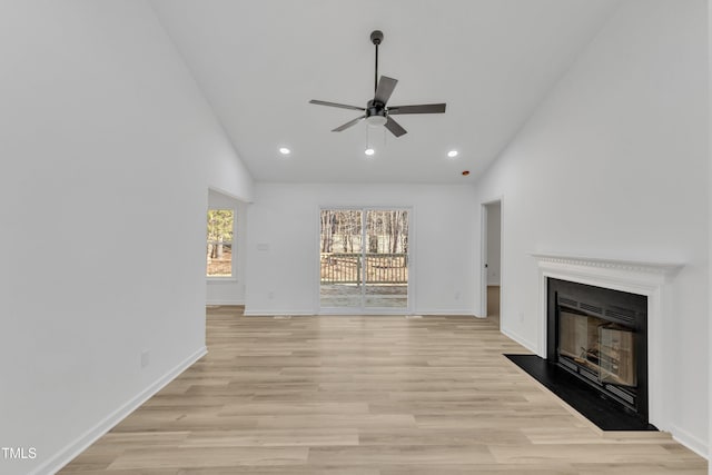 unfurnished living room featuring a fireplace with flush hearth, light wood-type flooring, baseboards, and a ceiling fan