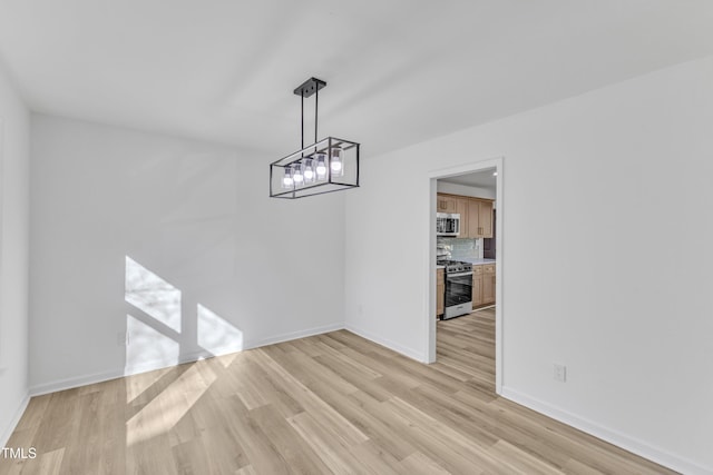 unfurnished dining area featuring light wood-style flooring and baseboards