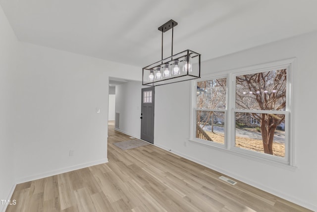 unfurnished dining area featuring baseboards, visible vents, and light wood finished floors