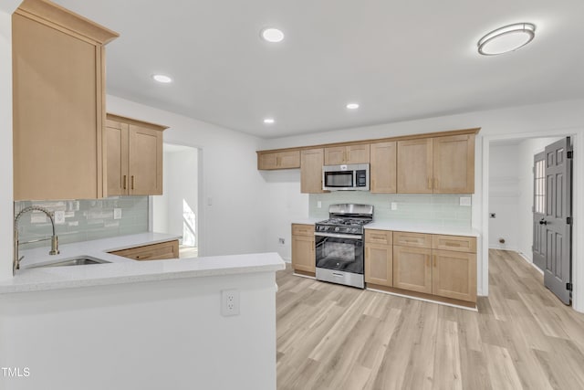 kitchen featuring recessed lighting, stainless steel appliances, a sink, light wood-style floors, and light countertops