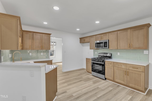 kitchen with light wood finished floors, stainless steel microwave, range with gas stovetop, and light countertops