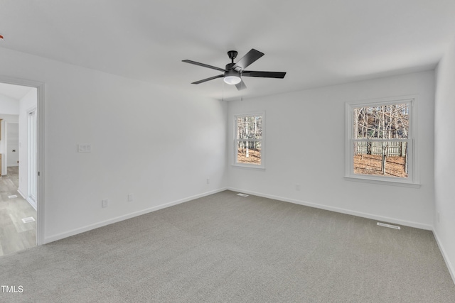 carpeted spare room with ceiling fan and baseboards