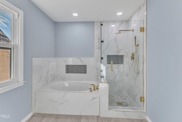 bathroom featuring a bath, a marble finish shower, a wealth of natural light, and baseboards