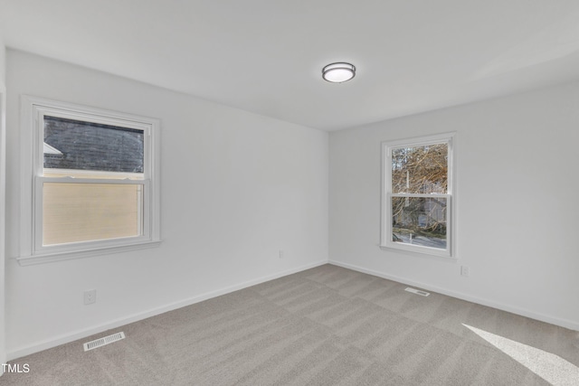 empty room featuring carpet, visible vents, and baseboards