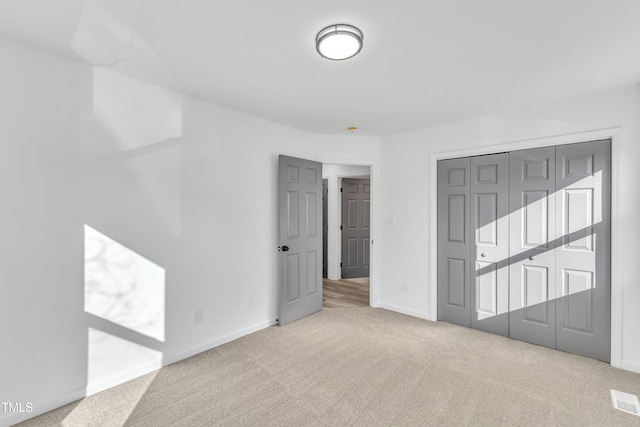 unfurnished bedroom with carpet floors, a closet, visible vents, and baseboards