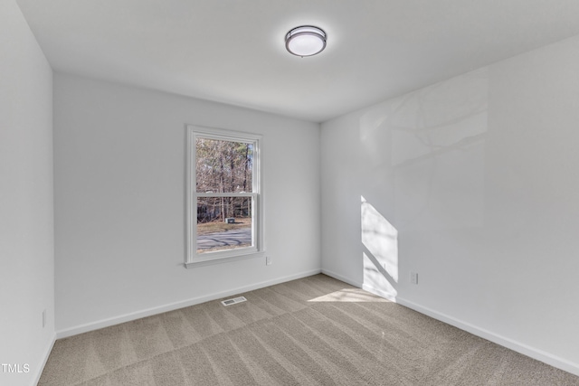 unfurnished room with carpet floors, visible vents, and baseboards