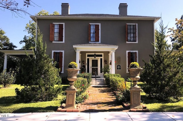 view of front of house featuring a chimney and stucco siding