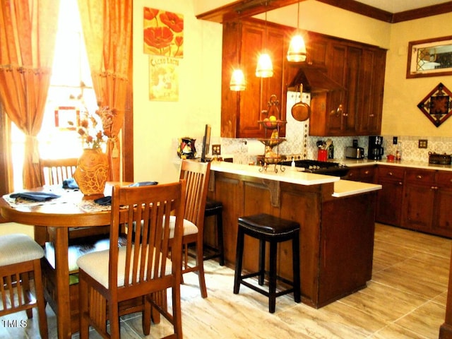 kitchen featuring a kitchen breakfast bar, decorative light fixtures, a peninsula, light countertops, and backsplash