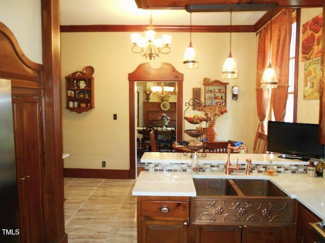 kitchen featuring hanging light fixtures, tasteful backsplash, light countertops, and a sink