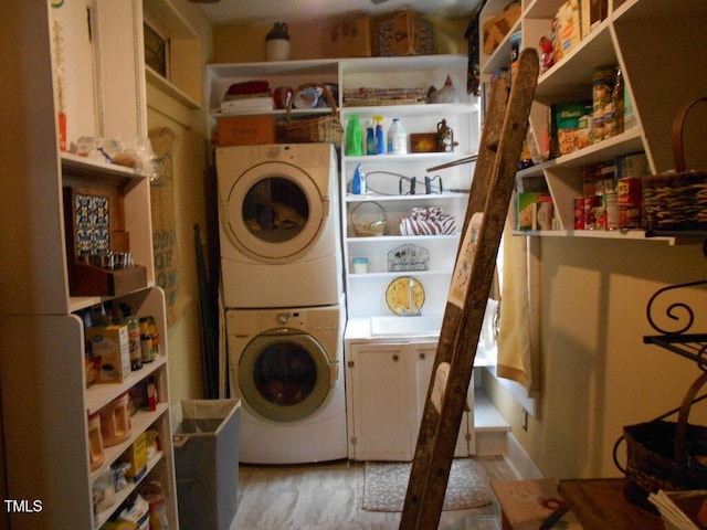 laundry room with laundry area, light wood finished floors, and stacked washer / drying machine