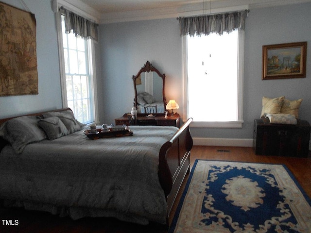 bedroom with ornamental molding, wood finished floors, and baseboards