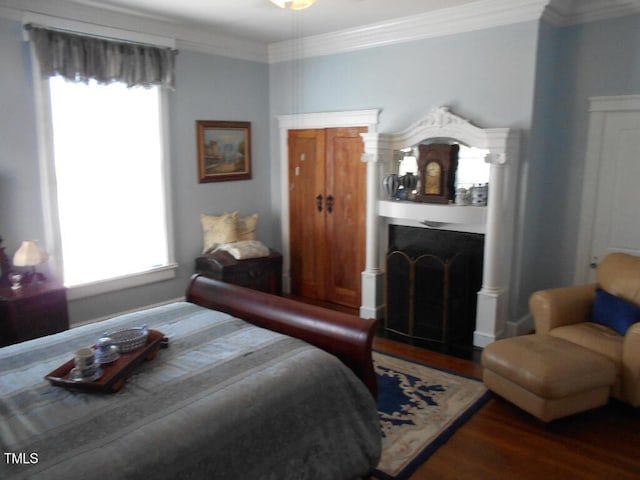 bedroom featuring dark wood-style floors, a fireplace with flush hearth, and crown molding