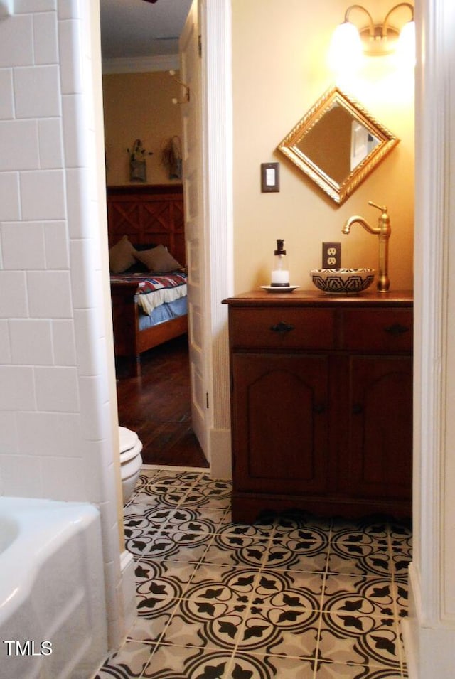 bathroom with connected bathroom, toilet, a tub, ornamental molding, and tile patterned floors