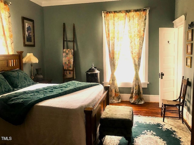 bedroom with baseboards, wood finished floors, and ornamental molding